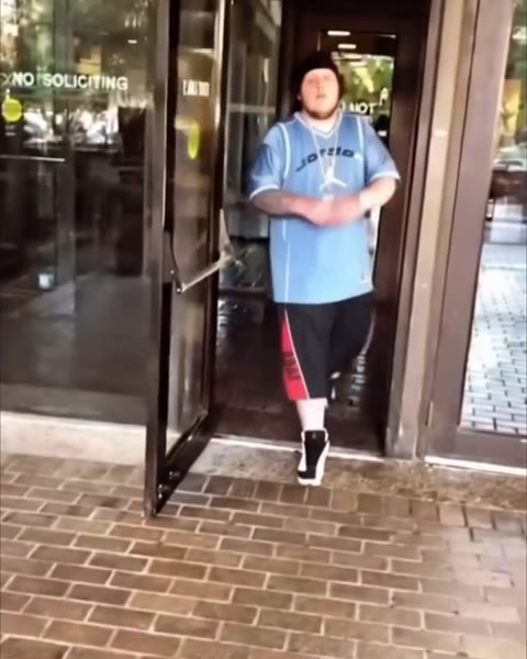 fat slime walking out through glass doors in a light blue jersey